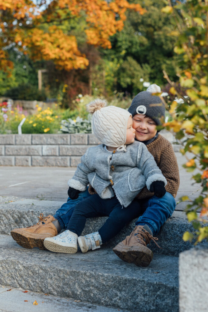 Sisaret istuvat portailla, taustalla syksyinen maisema.